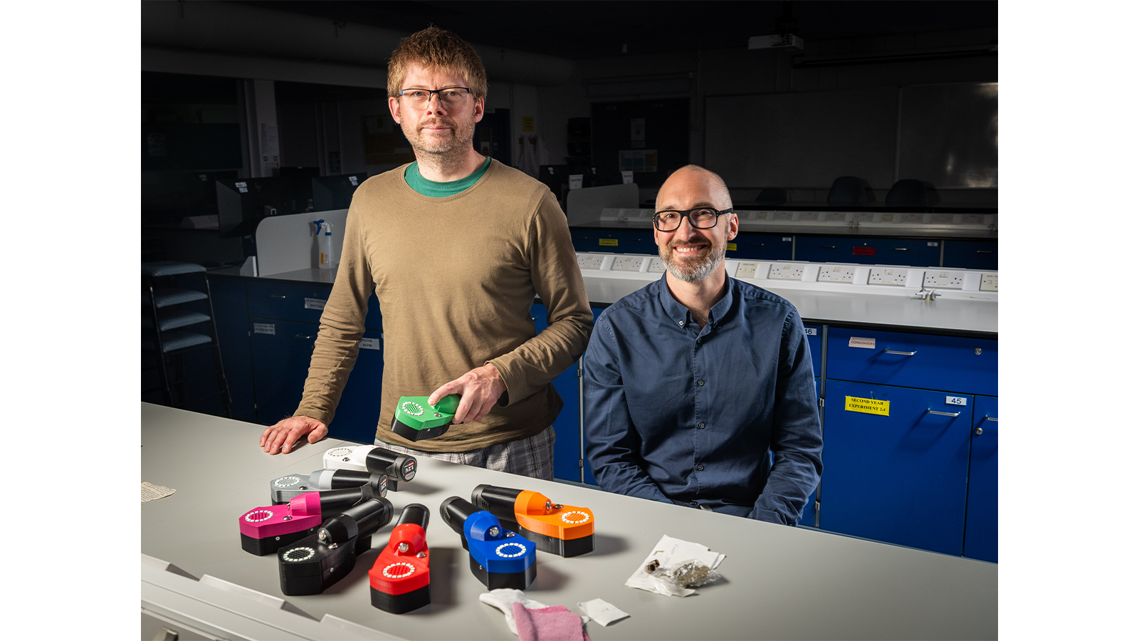 Two Harm Reduction team members standing with their equipment in a lab