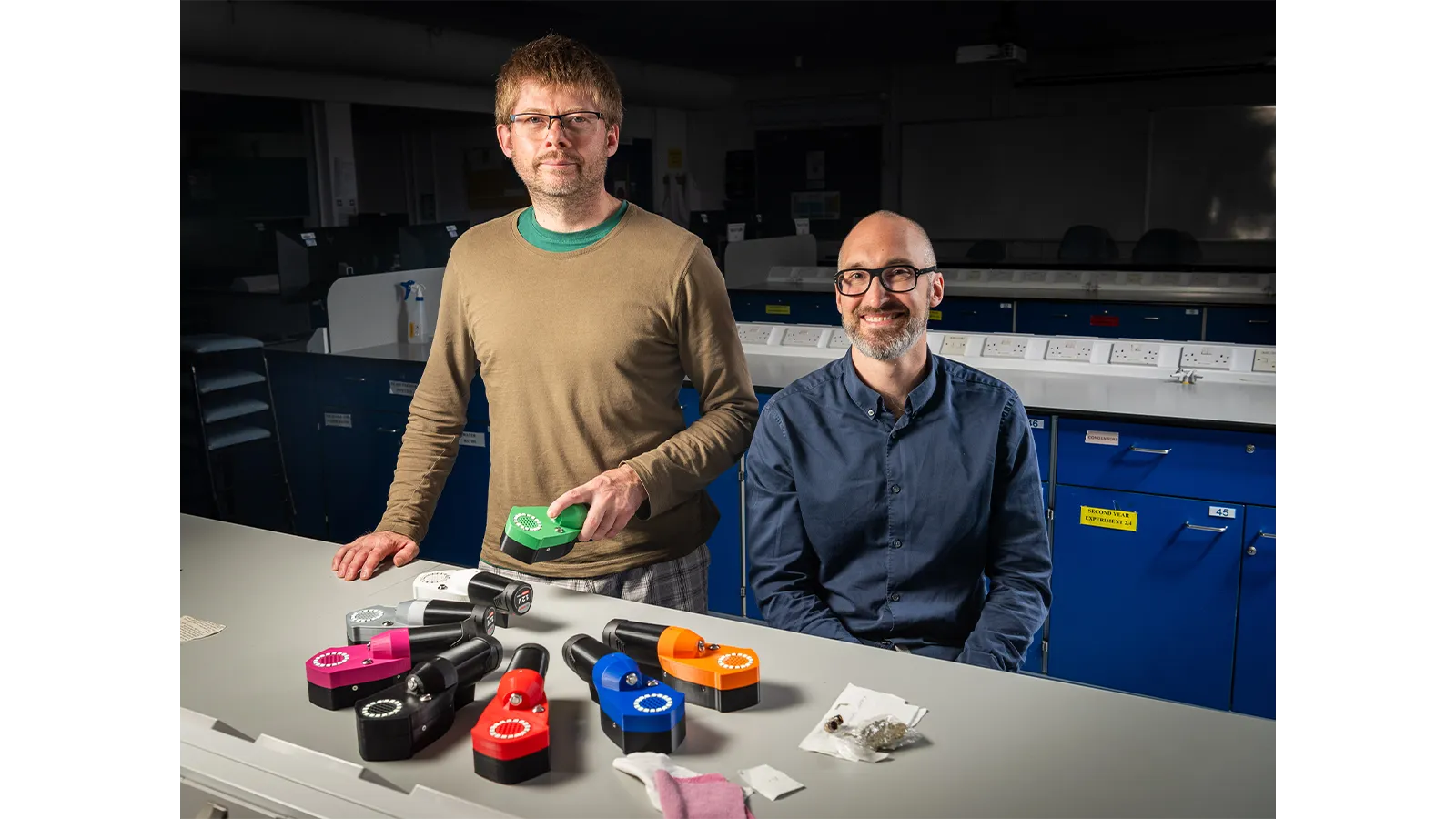 Two Harm Reduction team members standing with their equipment in a lab