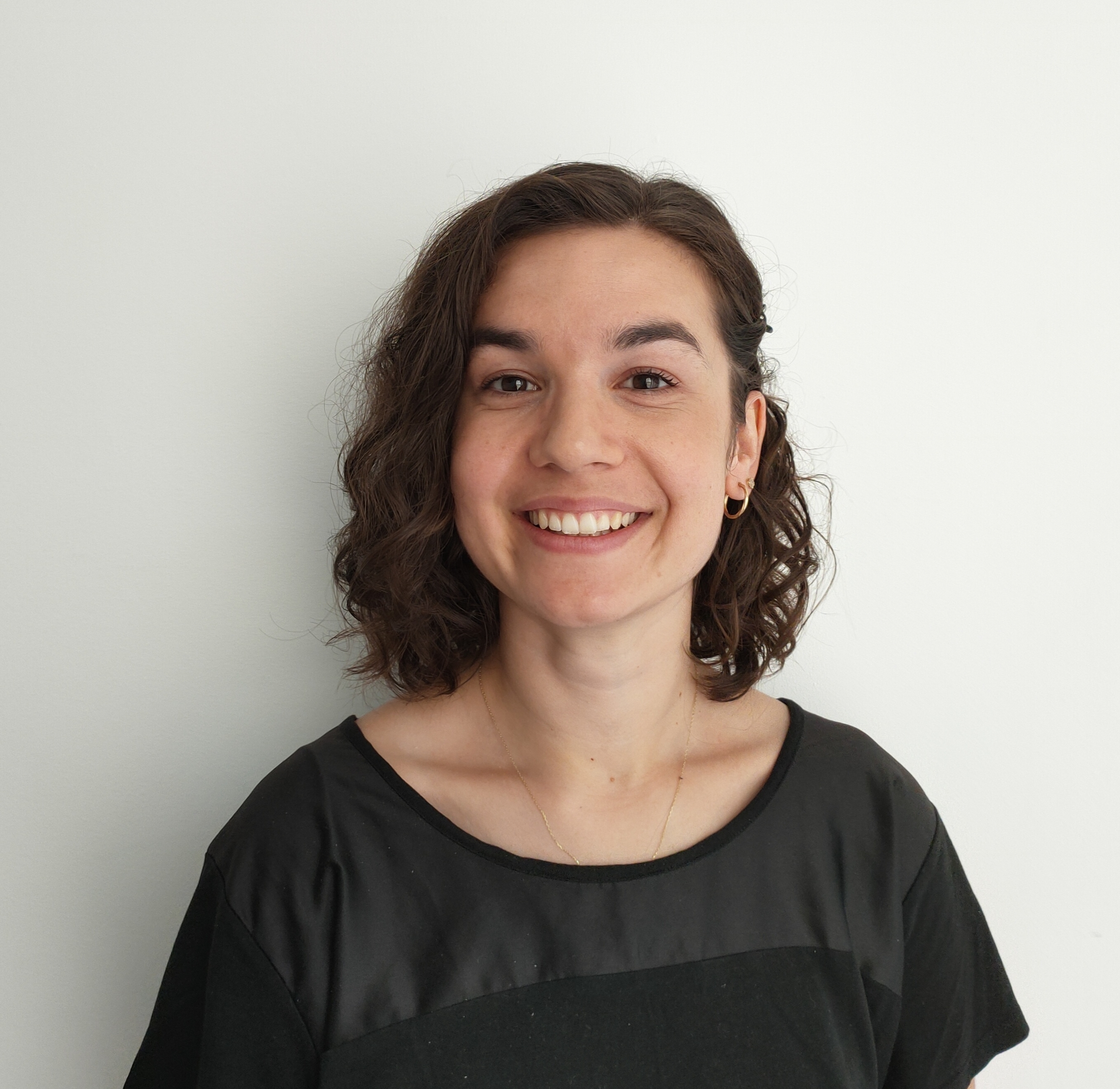 A head-and-shoulders picture of a smiling Aylin Ozkan wearing a black top and stood in front of a white background A head-and-shoulders picture of a smiling Aylin Ozkan wearing a black top and stood in front of a white background