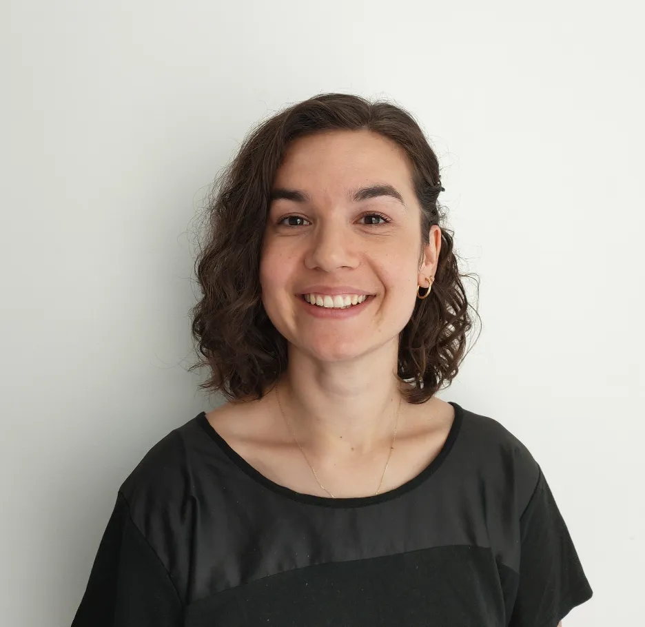 A head-and-shoulders picture of a smiling Aylin Ozkan wearing a black top and stood in front of a white background