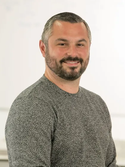 Dr Graeme Turnbull smiling to camera in grey sweater