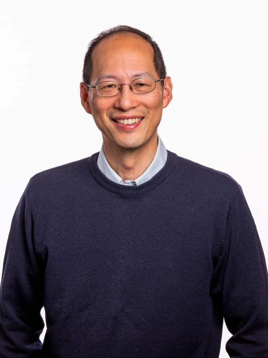 Professional portrait of Christopher Chang in shirt and jumper, wearing glasses