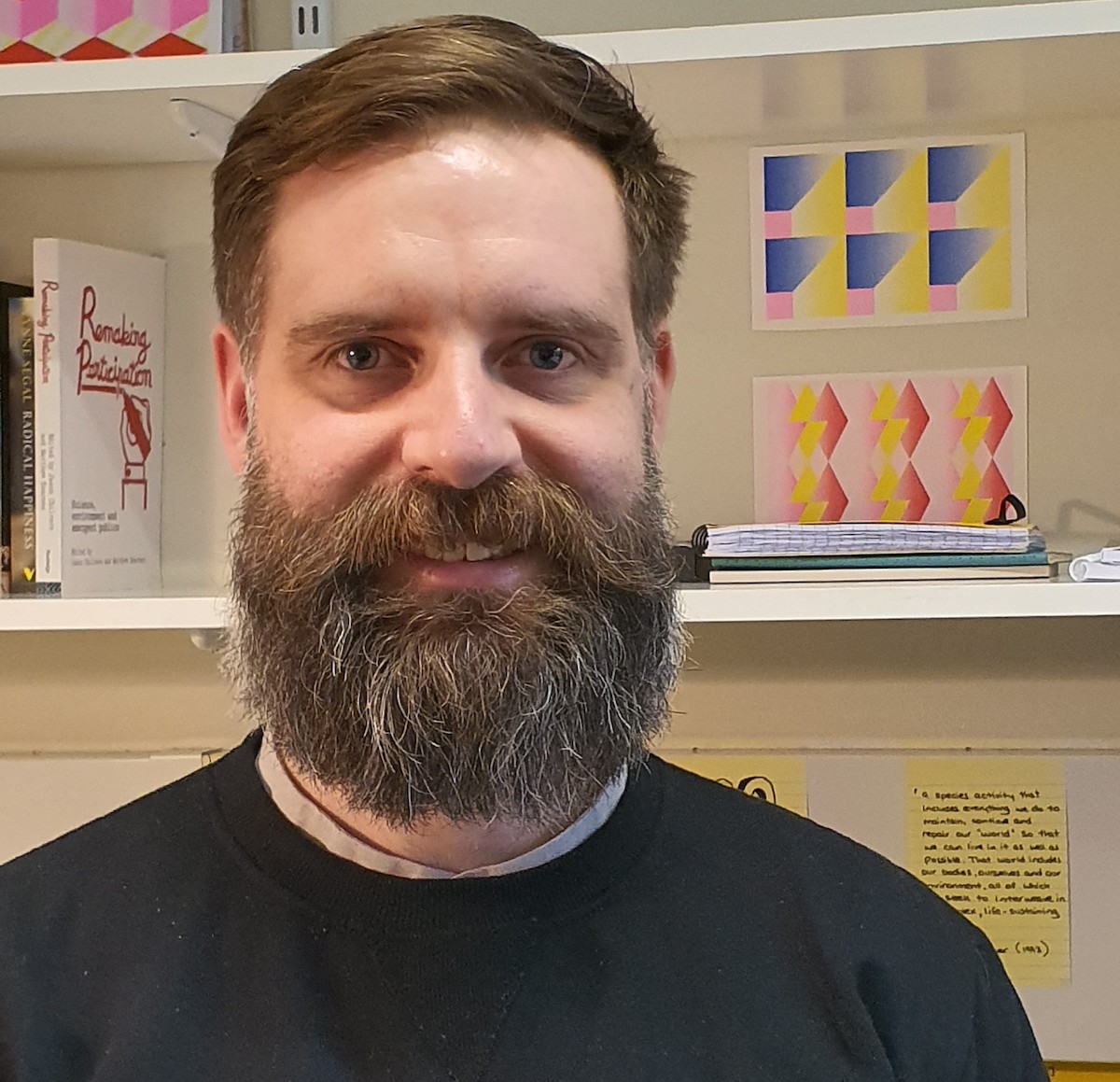 A portrait picture of Dr Stephen Hughes from the shoulders up, with a wall containing lab equipment behind him.