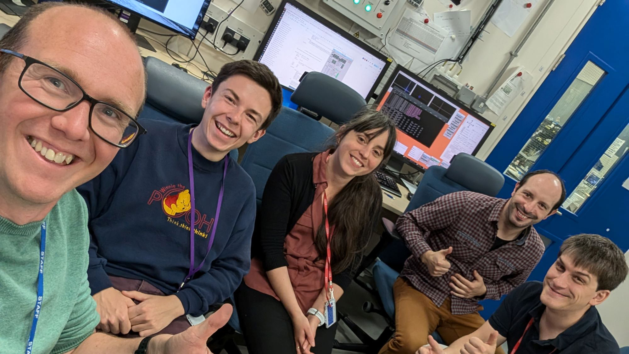 Dr Lauren Hatcher with a group of people sitting in chairs, all smiling for the camera