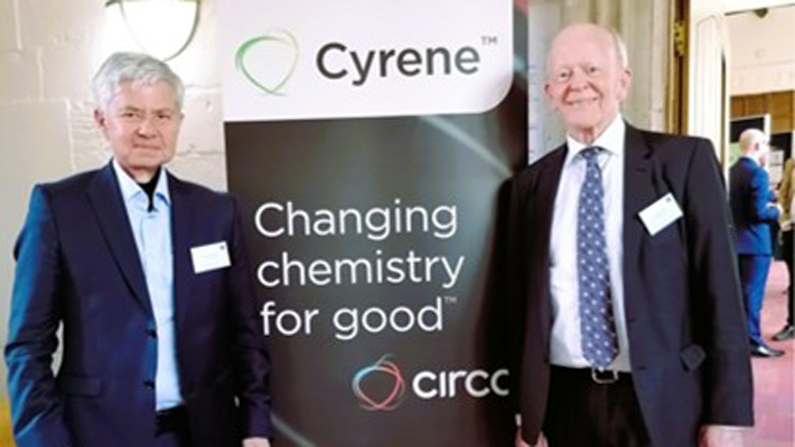Two of Green Circular Solvent Team standing in front of a sign with text "Changing chemistry for good"