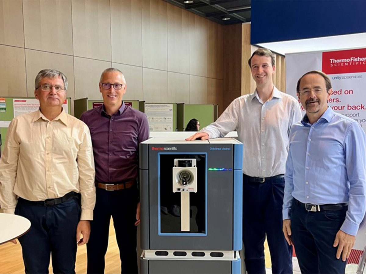 Orbitrap Astral male team members standing next to one of their machines