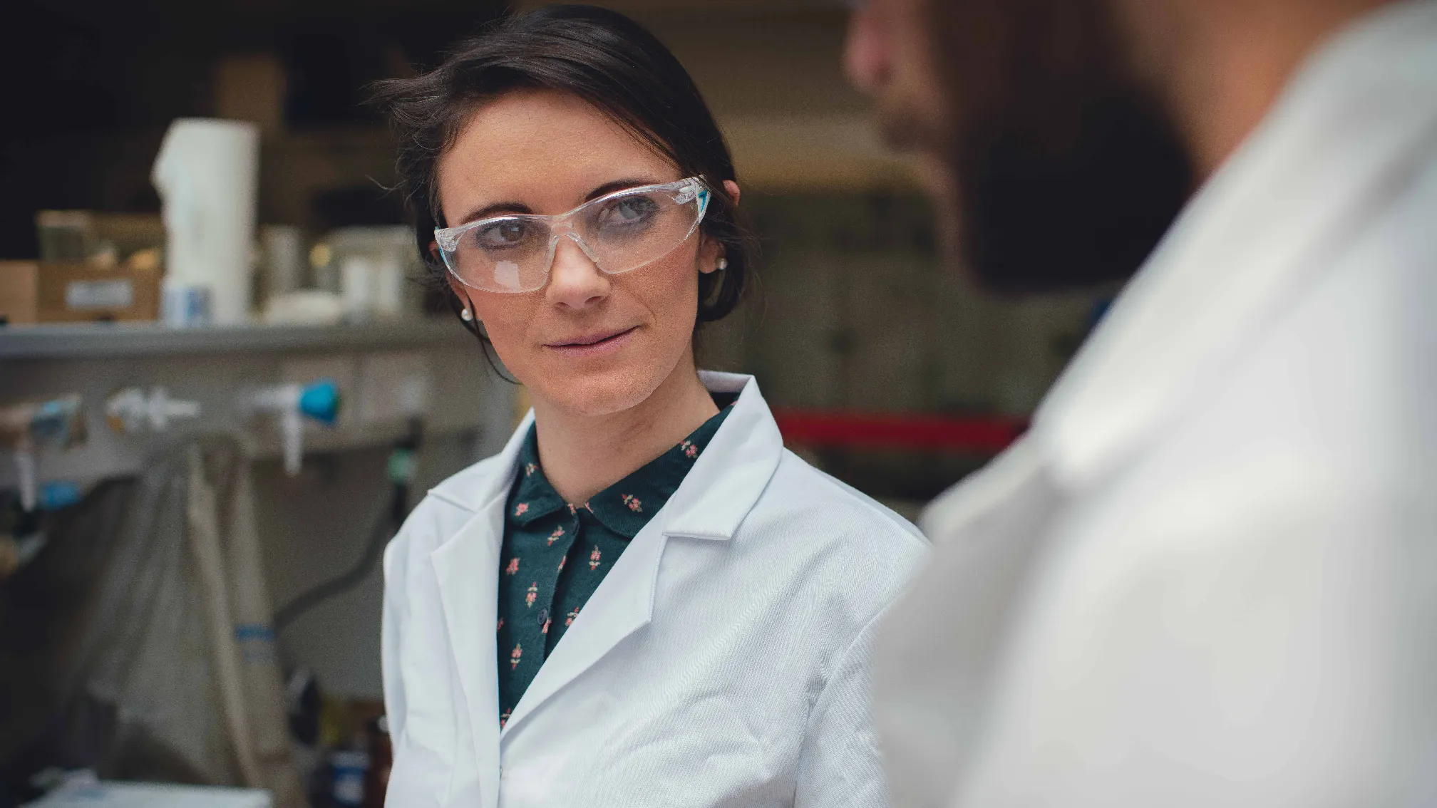 Professor Rebecca Melen wearing white lab coat and goggles in lab