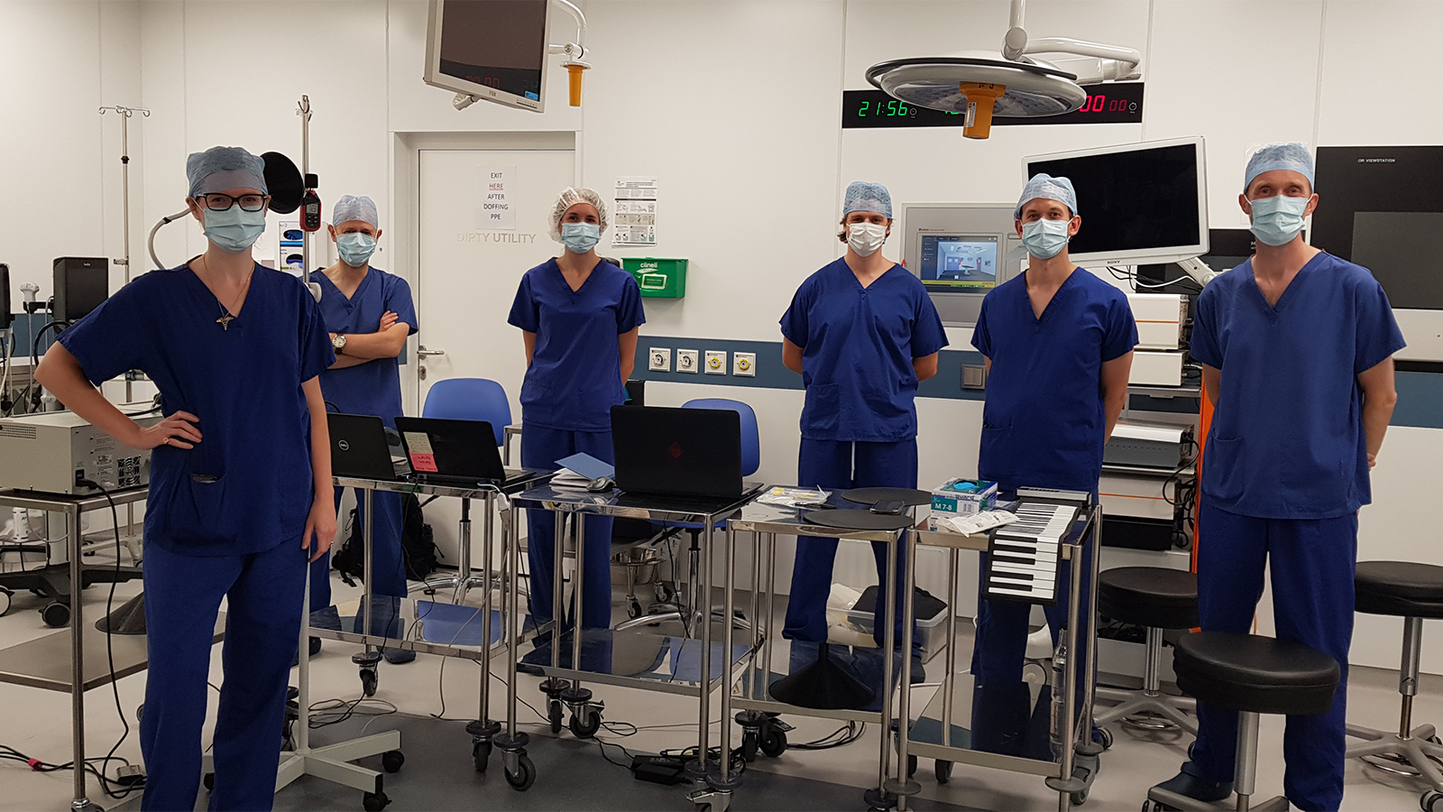 The PERFORM COVID-19 Team wearing scrubs and masks standing up for the camera in the lab