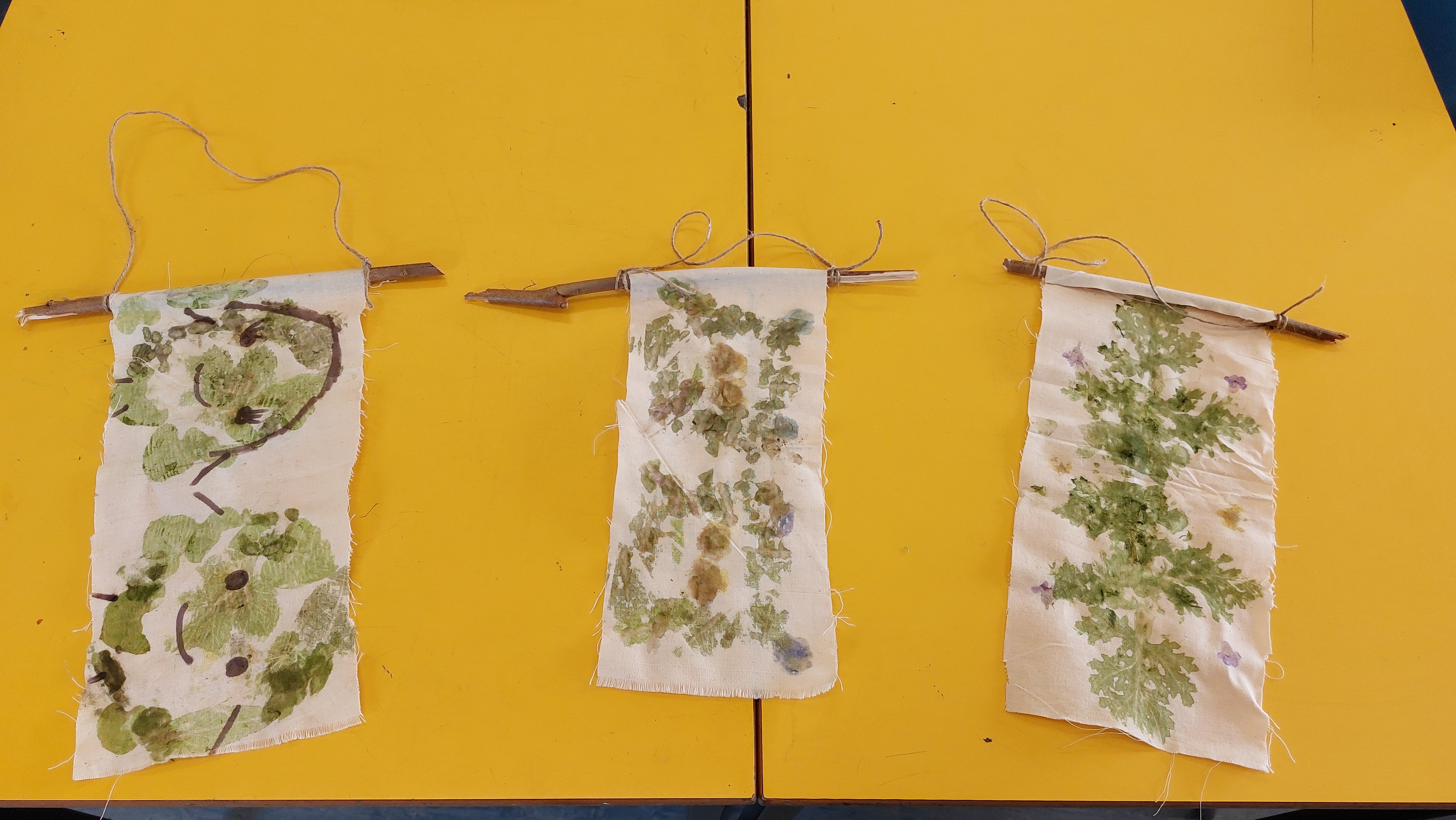 Three pieces of artwork made on cloth with natural artifacts.