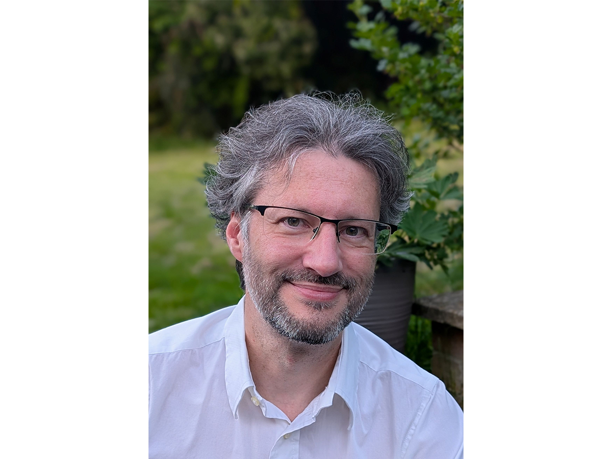 Professor Igor Larrosa wearing white shirt and glasses smiling for camera