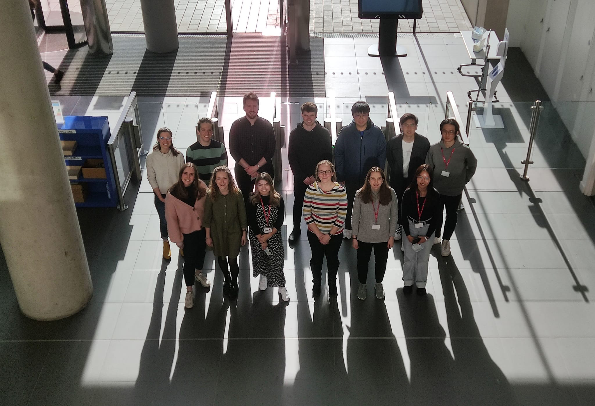 Professor Kim Jelfs with a group of people standing together on a lower floor looking up at photographer