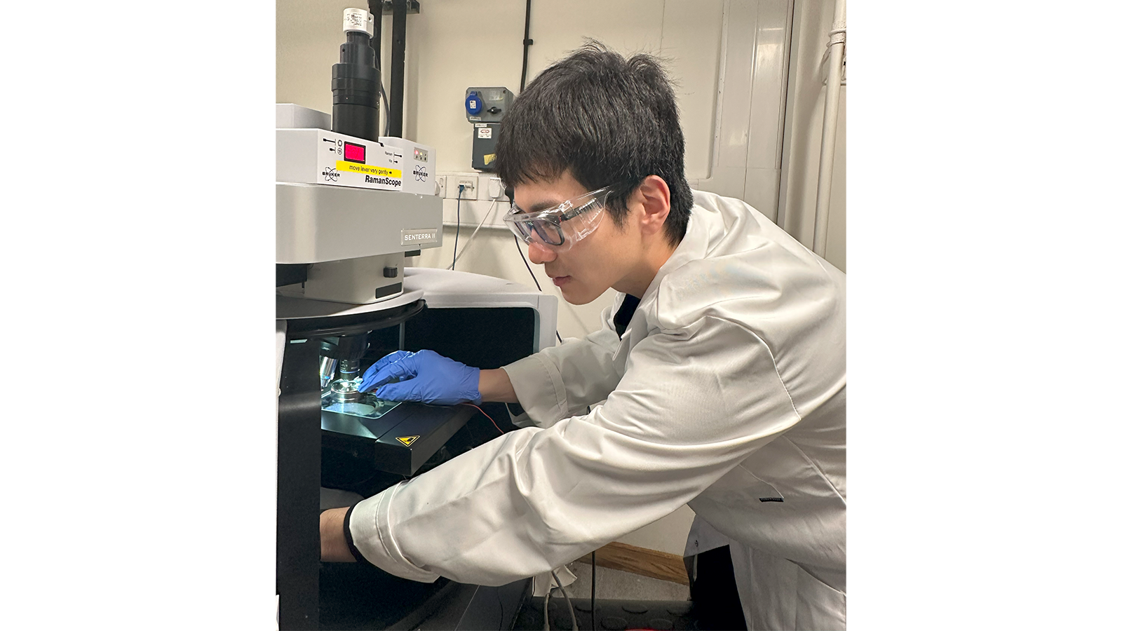 Dr Guanjie He wearing goggles and gloves working in a laboratory