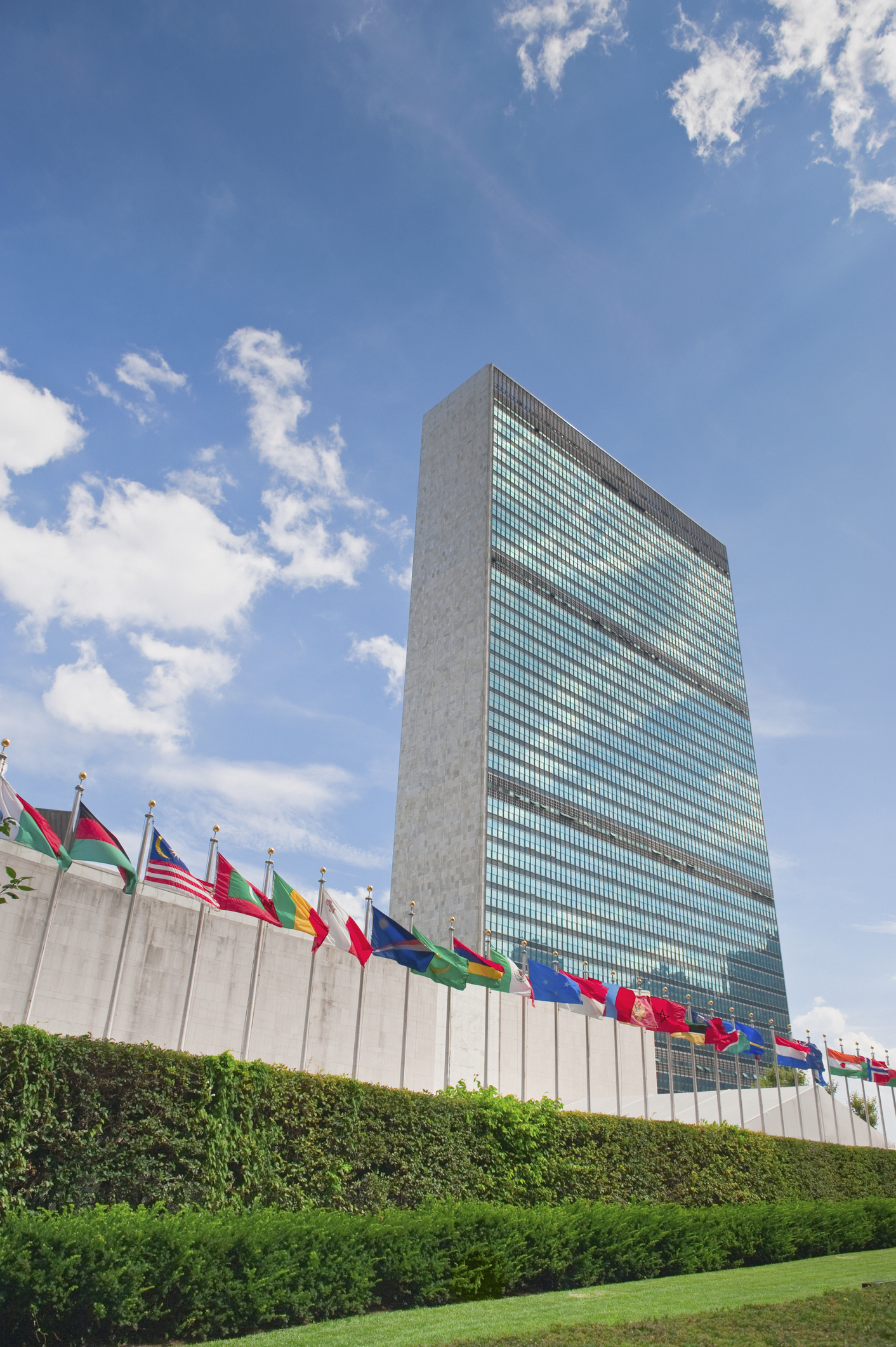 A row of flags flap in the breeze in front of the United Nations HQ building in New York A row of flags flap in the breeze in front of the United Nations HQ building in New York
