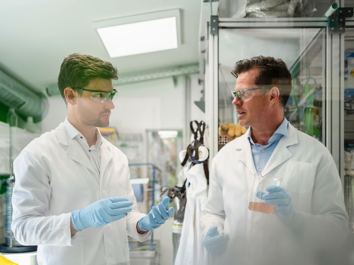 Two male chemists in lab with flasks