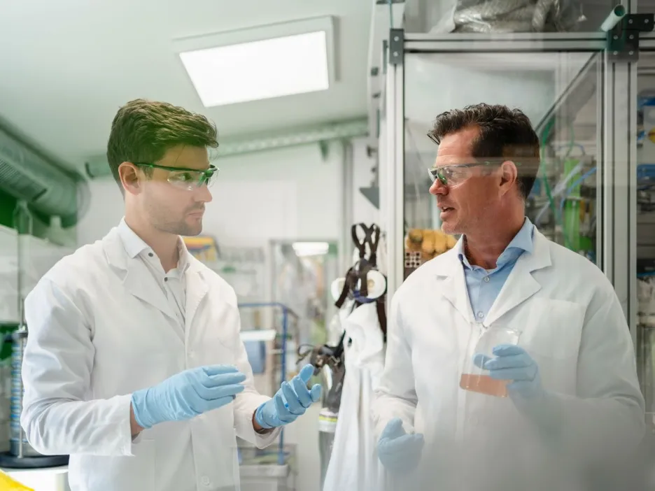 Two male chemists in lab with flasks