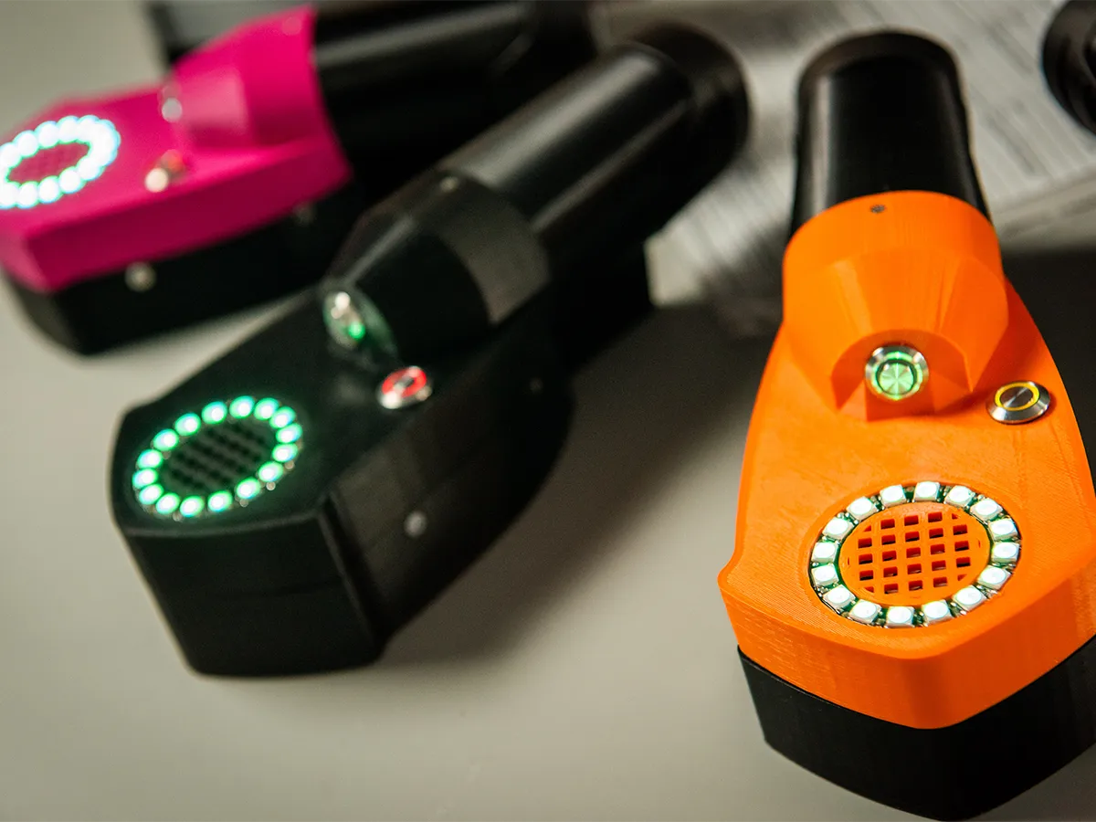Harm Reduction drug testing devices in orange green and pink, with lights on in a circle
