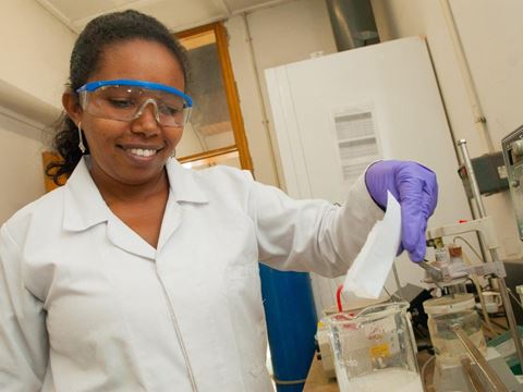 Smiling female scientist in a lab holding a note in hand 
