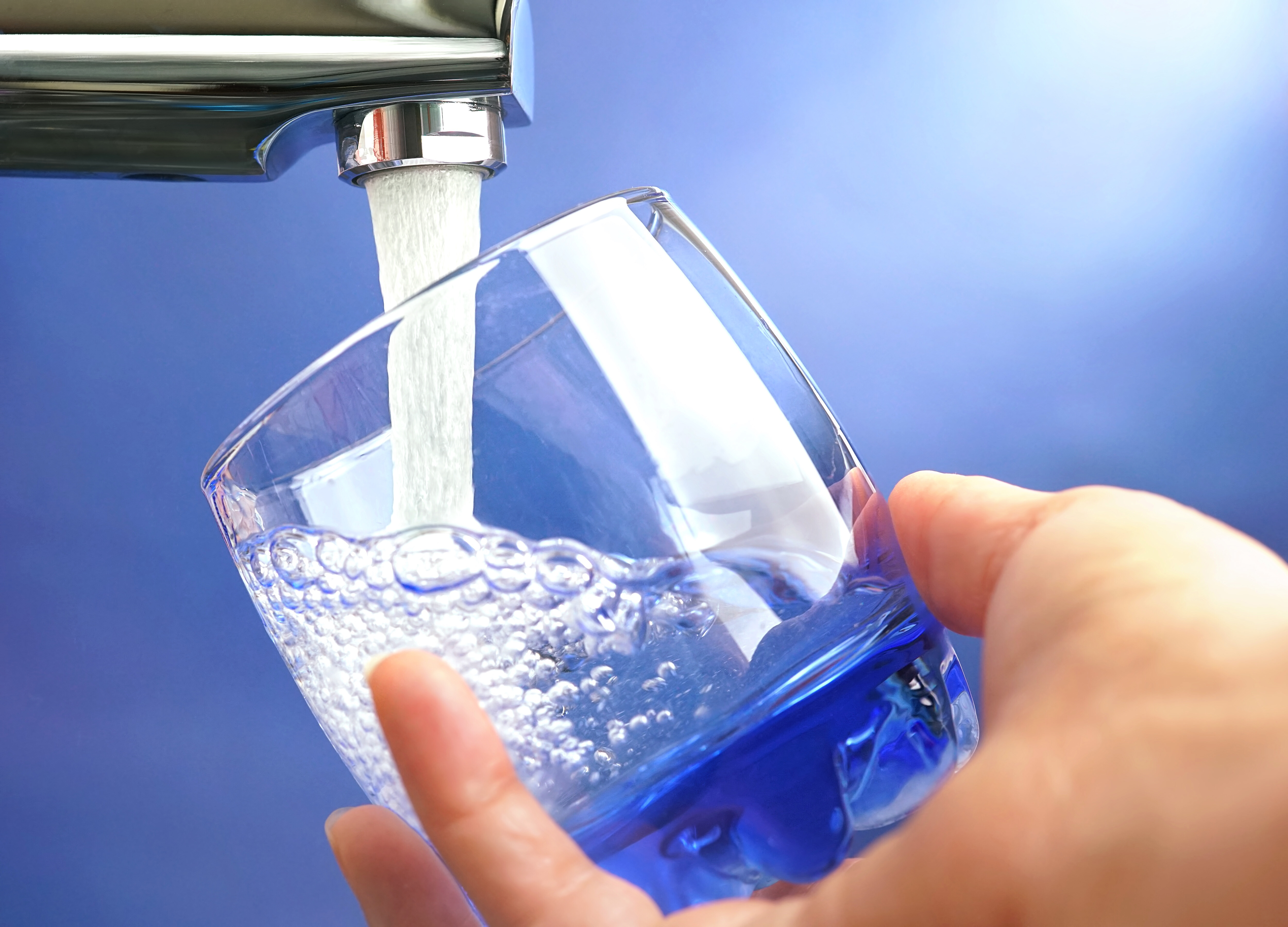 A hand holds a glass as a tap fills it with water A hand holds a glass as a tap fills it with water