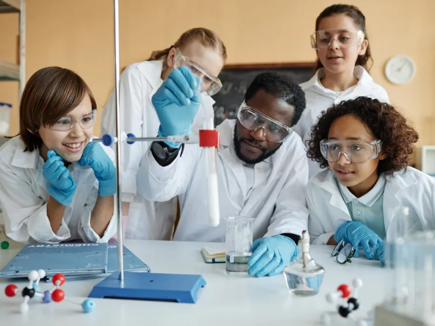 Young teacher demonstrating lab experiment to kids in a lab setting