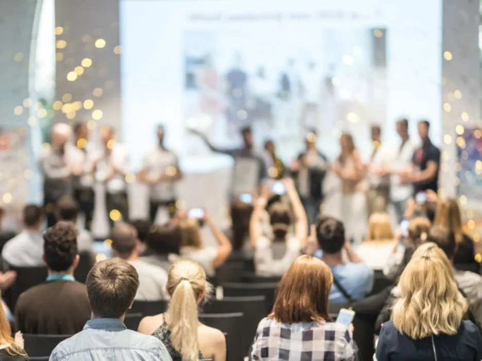 People celebrating in a competition or award ceremony and people in audience taking photos