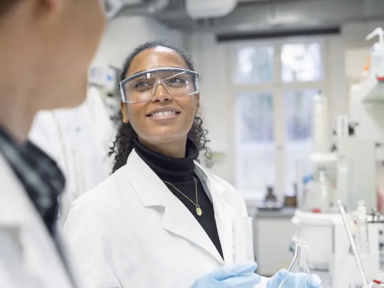 Smiling scientists talking to each other in laboratory