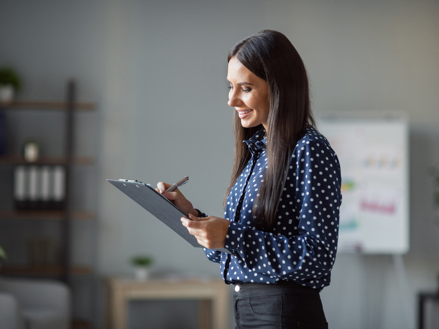 Smiling female professional writing on clipboard in an office