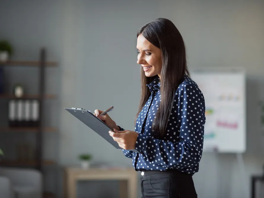 Smiling female professional writing on clipboard in an office