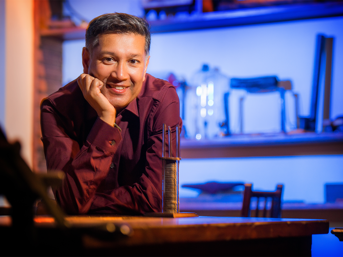 Professor Saiful Islam with his hand on his chin, wearing red shirt and smiling for camera
