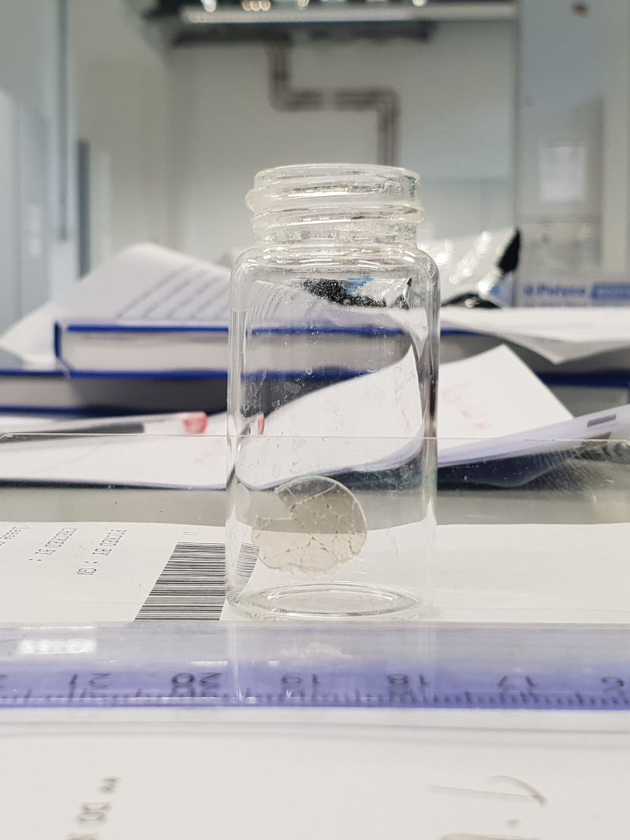 A glass jar on a table with papers of data in the Pioneers in Hybrid Glass Research lab