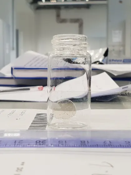 A glass jar on a table with papers of data in the Pioneers in Hybrid Glass Research lab