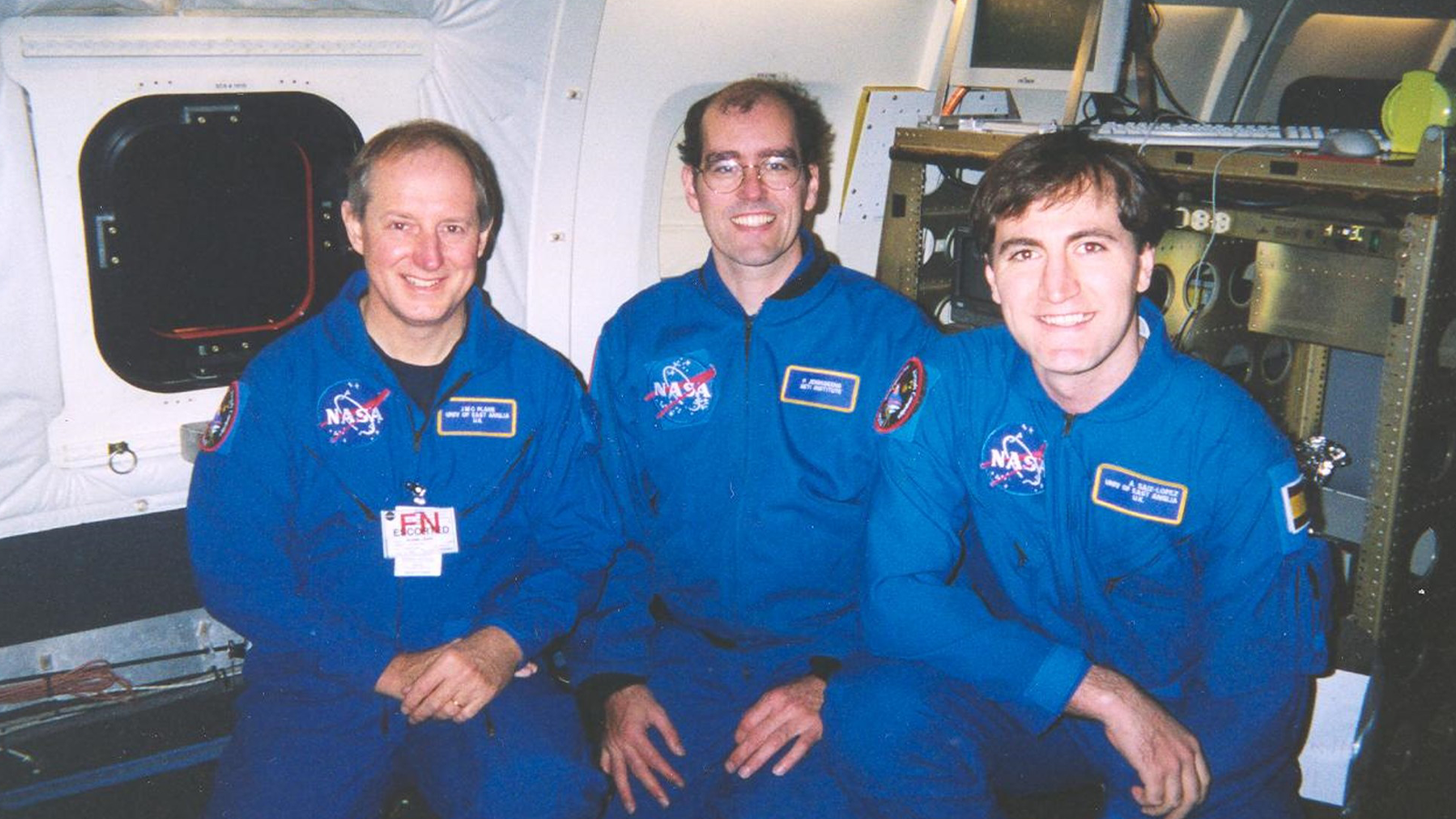 Professor John Plane with colleagues in blue jumpsuits with logo