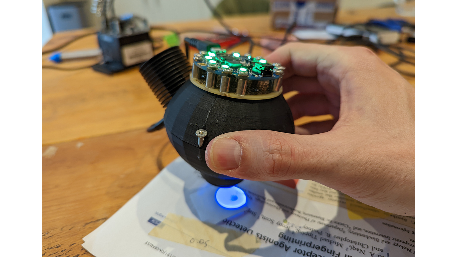 a hand holding a small black object with green lights