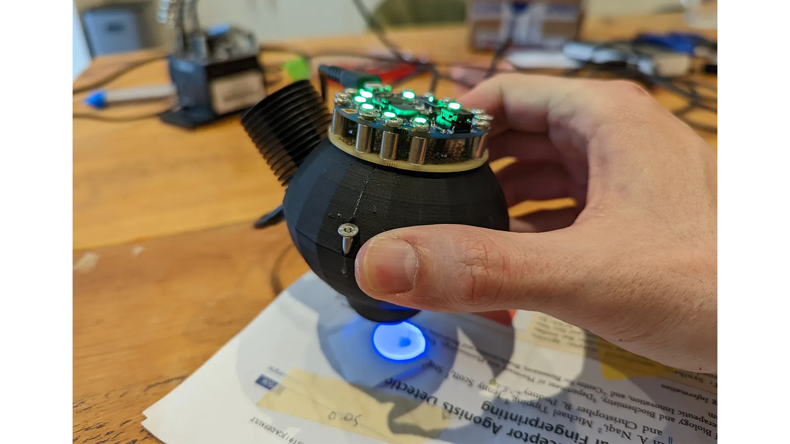 a hand holding a small black object with green lights