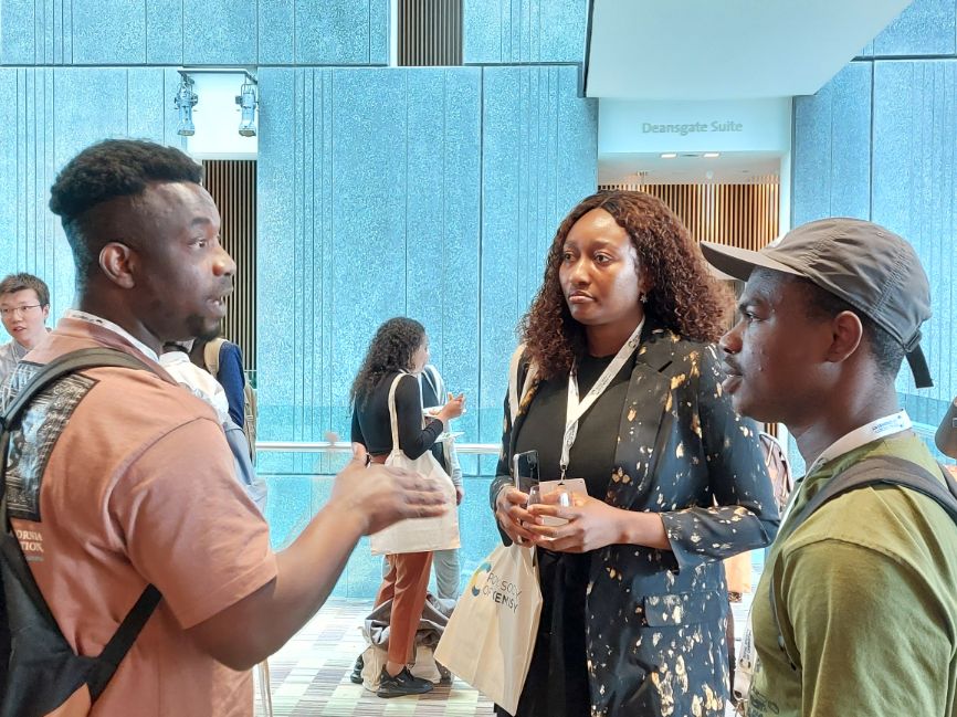 Three participants stand in a group, talking to each other