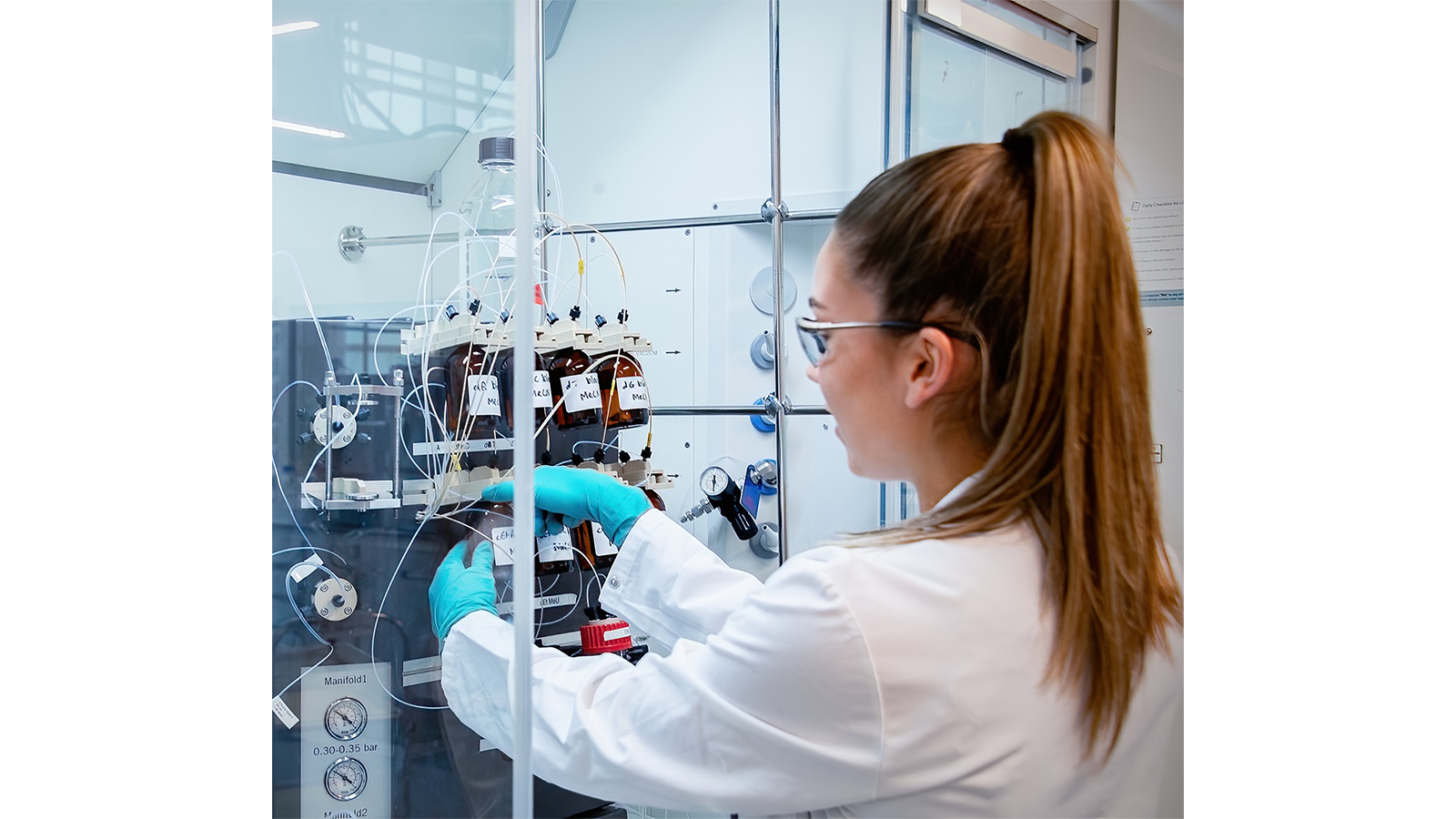 Georgia Wignall in in a lab coat and gloves working on a machine