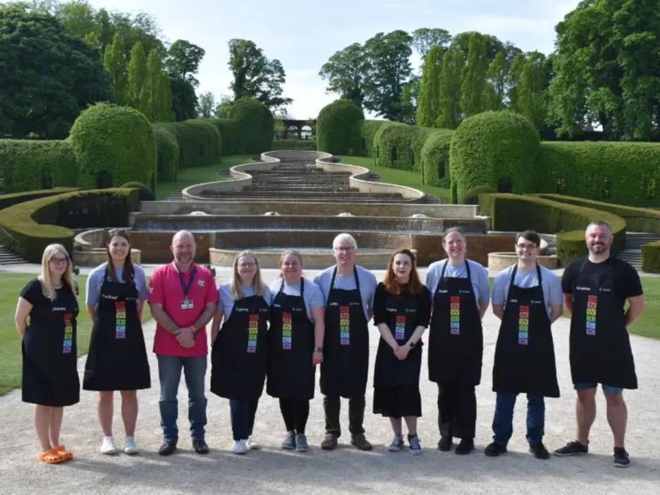 Ten volunteers in aprons in manicured gardens of alnwick