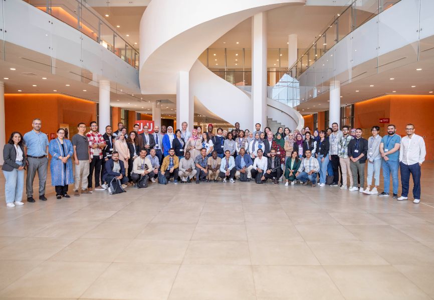 Around 50 or 60 participants of the GreenChemAfrica training school pose and smile in the reception area of a large, white, modern building Around 50 or 60 participants of the GreenChemAfrica training school pose and smile in the reception area of a large, white, modern building